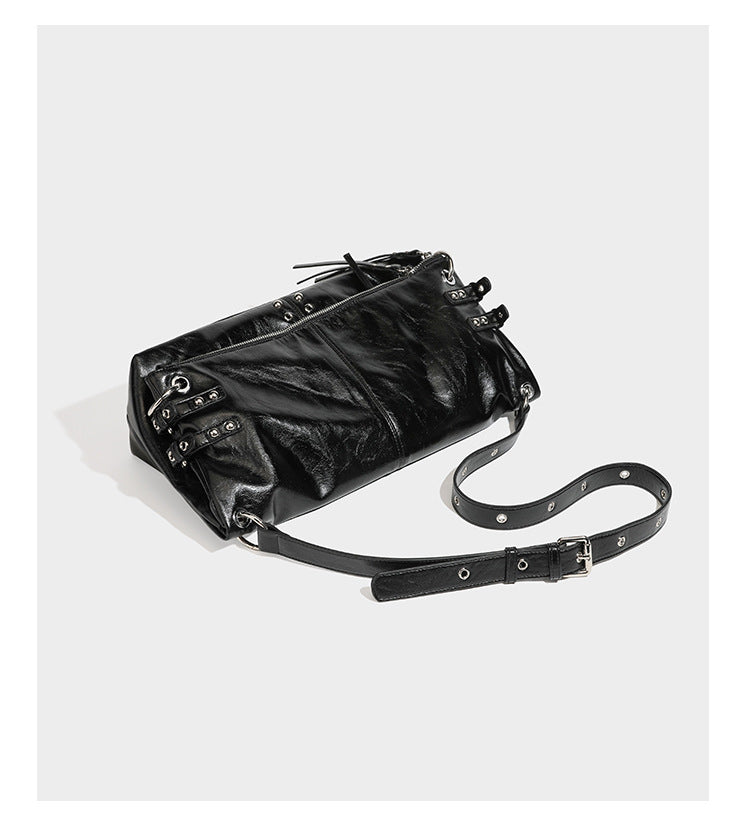 Black glossy leather-look slouchy shoulder bag with silver stud and eyelet hardware, top zip closure, front zip pocket, and