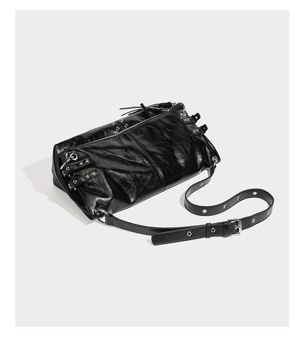 Black glossy leather-look slouchy shoulder bag with silver stud and eyelet hardware, top zip closure, front zip pocket, and