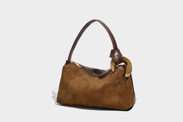 Kompakte Boston-Schultertasche in warmem Braun in Wildlederoptik mit glattem dunkelbraunem Besatz, übergroßen goldfarbenen Ringelementen und Reißverschluss oben