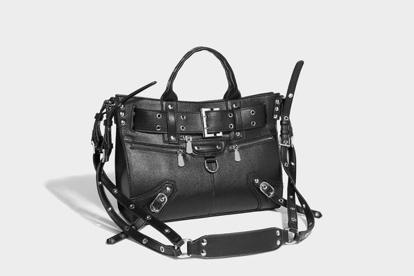 Black structured rectangular satchel bag with silver-tone rivets, large front buckle strap, zip pockets, dual top handles