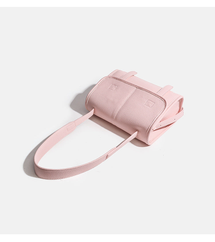 Compact structured flap satchel bag with pebbled texture, snap closure, front strap tabs, and long adjustable crossbody