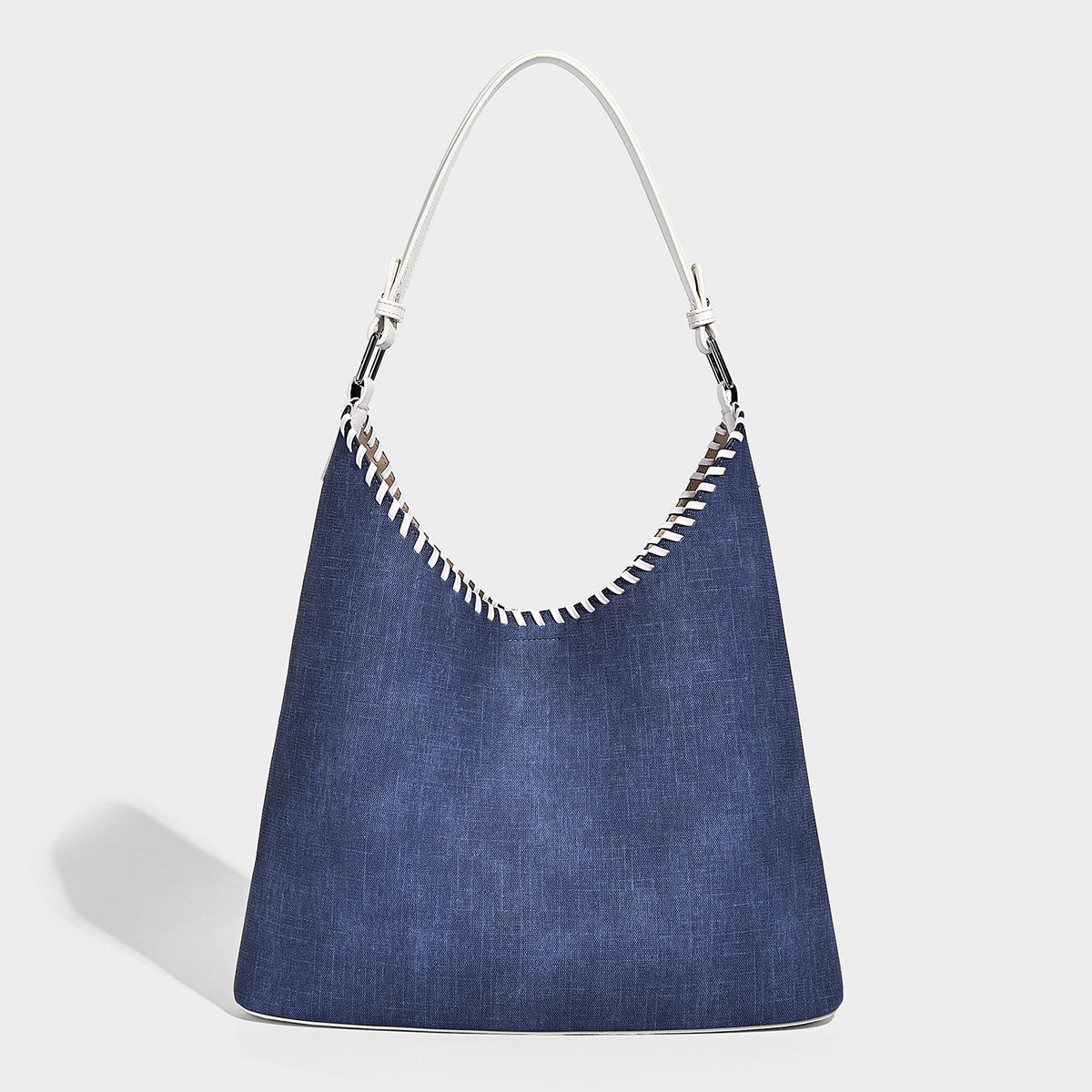 Denim-blue hobo tote with white leather-look shoulder strap, contrast whipstitch trim along curved open top, and silver-tone