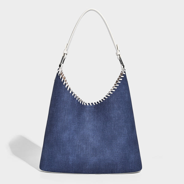 Denim-blue hobo tote with white leather-look shoulder strap, contrast whipstitch trim along curved open top, and silver-tone