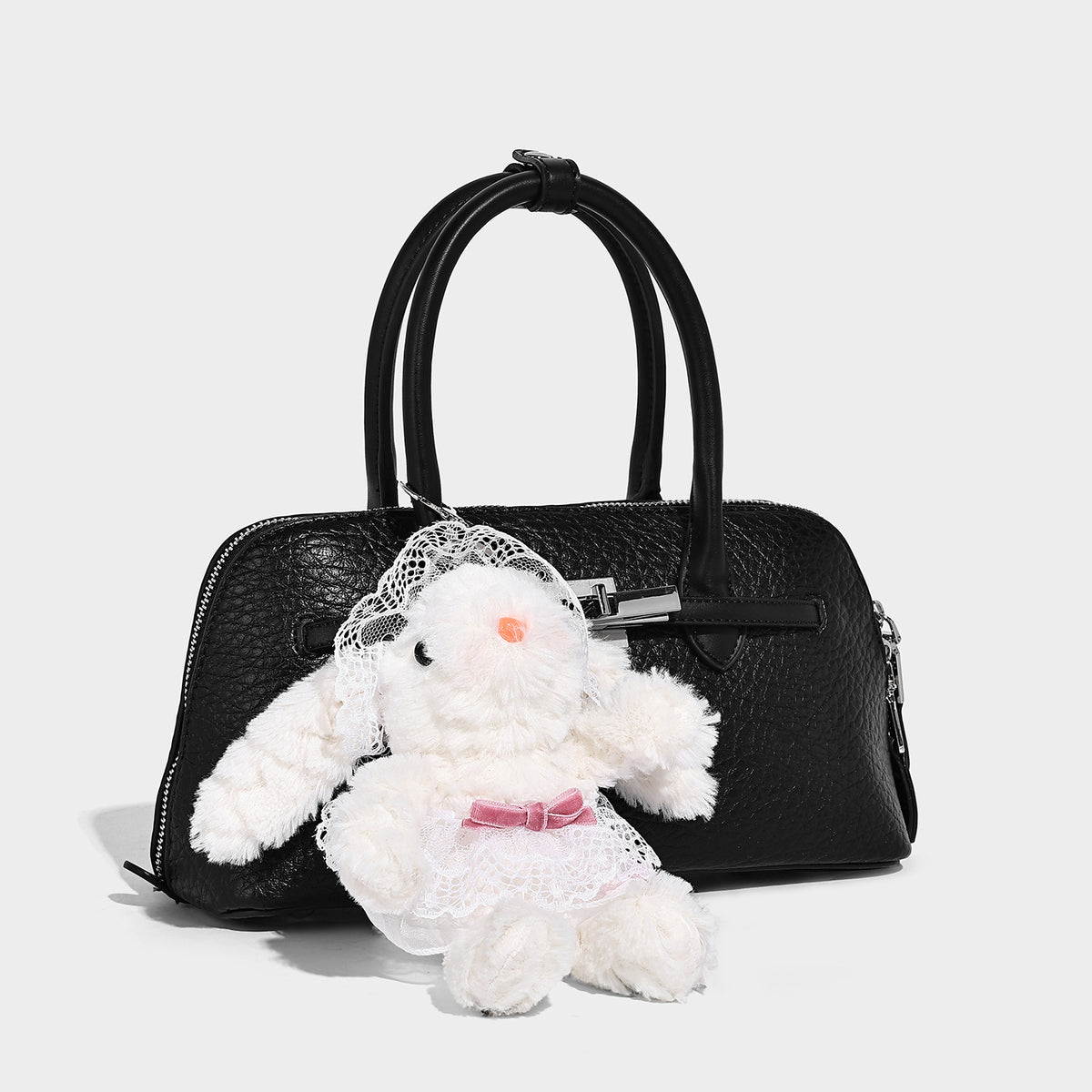 Small structured shell-silhouette top-handle bag with pebbled leather-look finish, silver-tone turn-lock hardware, and