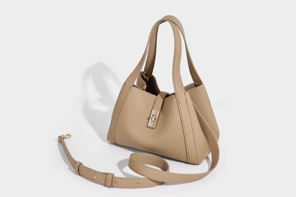 Structured trapezoid tote bag in taupe pebbled leather-look finish with gold-tone turn-lock hardware, dual top handles, and