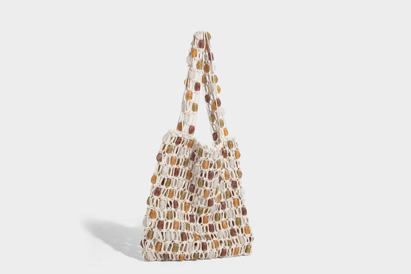Cream macramé open-weave tote bag with multicolor amber olive and translucent bead accents and woven shoulder straps, detail