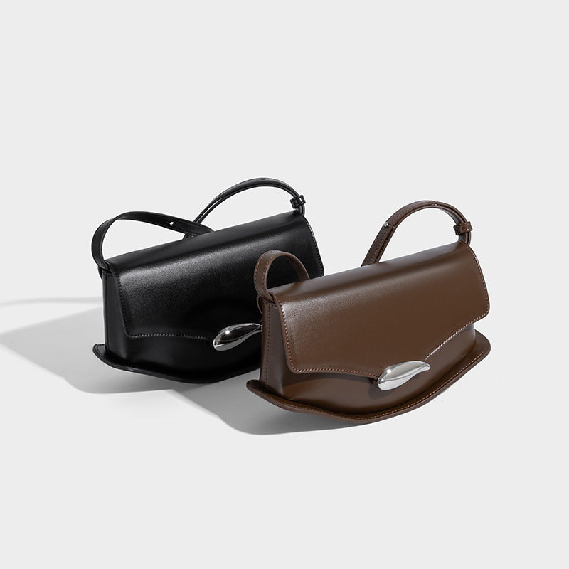 Small structured saddle bag with glossy leather-look finish, angular flap front, silver-tone metal clasp, and slim