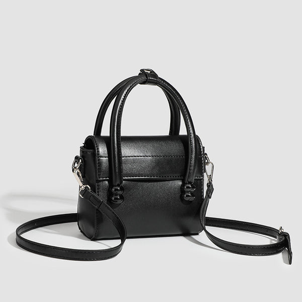 Kleine strukturierte schwarze Henkeltasche im Lederlook mit zwei abgerundeten Henkeln, abnehmbarem Umhängeriemen und silberfarbenem