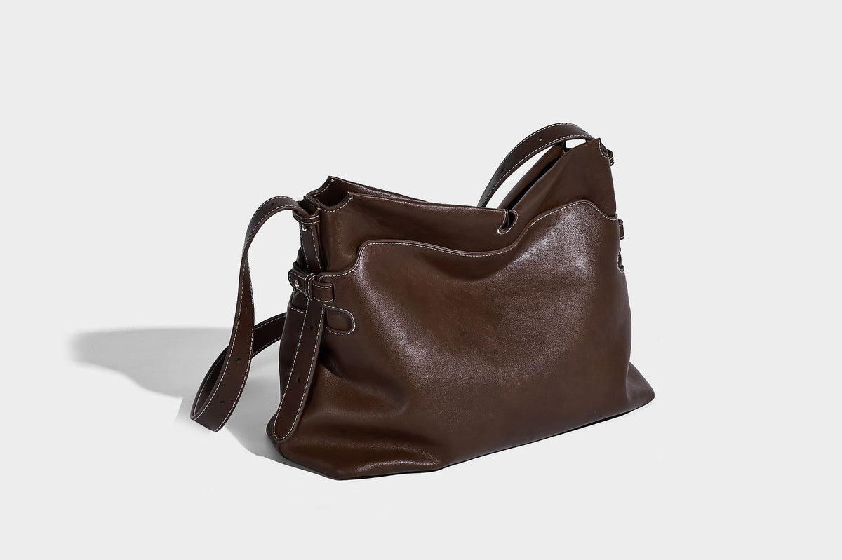 Large slouchy leather-look hobo tote bag with open top, adjustable shoulder strap, and colorful tassel bead charm, detail