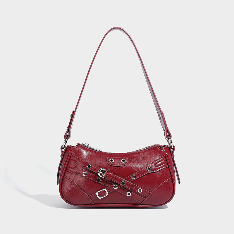 Compact moto-inspired shoulder bag with crisscross grommet strap detail, glossy textured finish, and adjustable crossbody