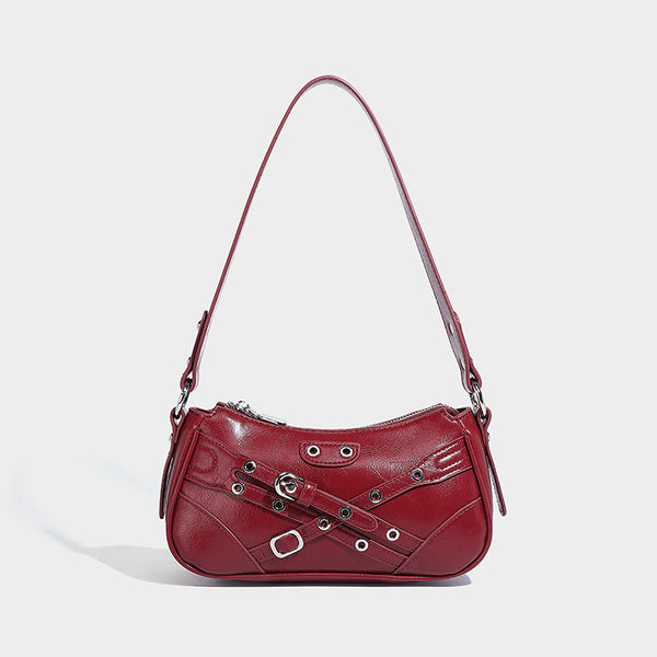Compact moto-inspired shoulder bag with crisscross grommet strap detail, glossy textured finish, and adjustable crossbody