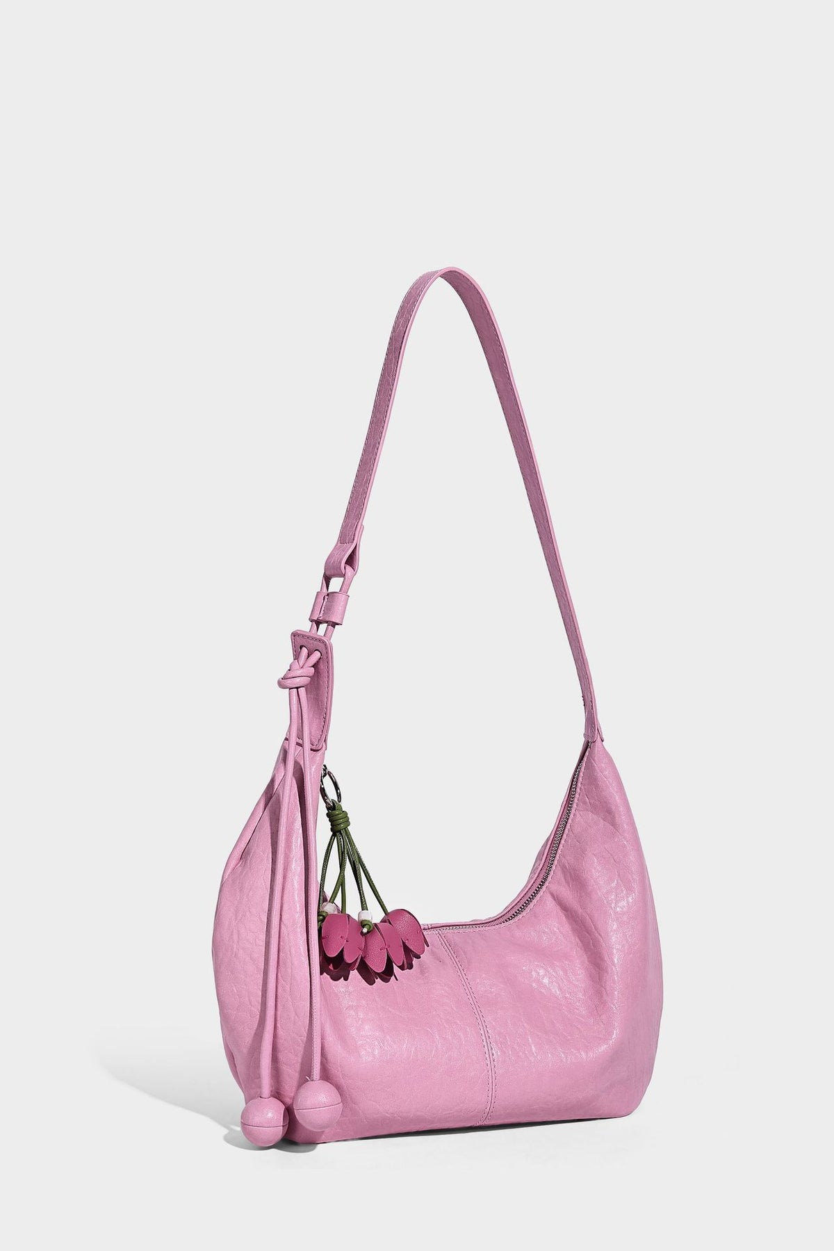 Slouchy crescent half-moon shoulder bag in pink pebbled textured finish with floral charm and knotted side detail, detail