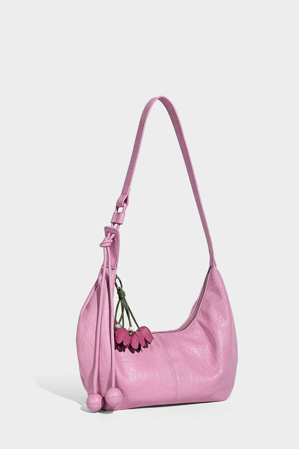 Slouchy crescent half-moon shoulder bag in pink pebbled textured finish with floral charm and knotted side detail, detail