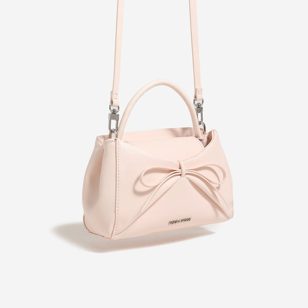 Structured mini trapezoid top-handle crossbody bag with sculpted bow front detail, smooth matte finish, silver-tone hardware