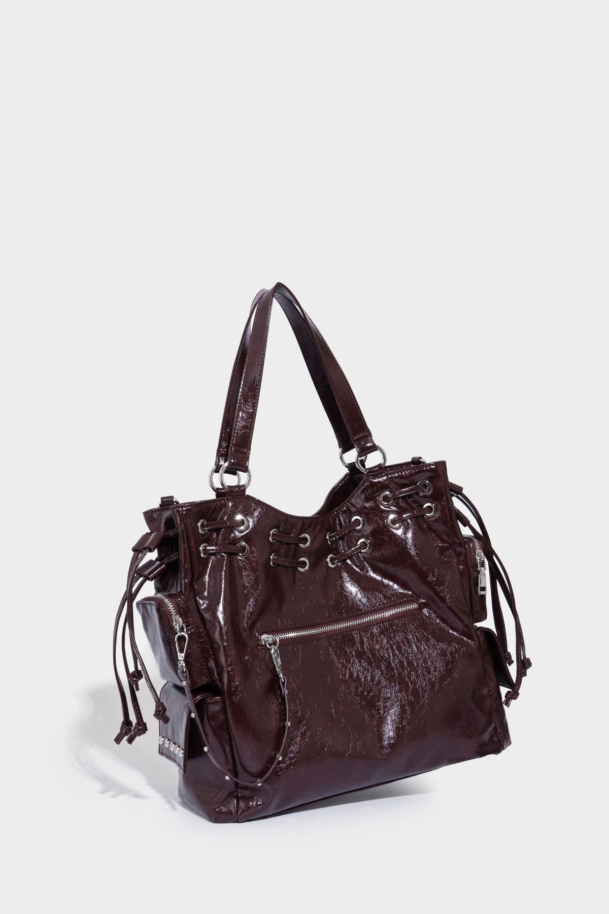 Glossy crinkled leather-look tote bag with silver grommet lace-up front detail, dual top handles, and detachable shoulder
