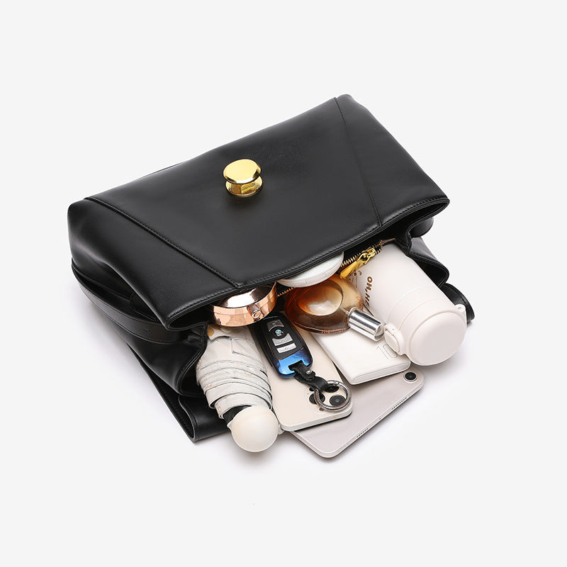 Structured flap shoulder bag with round gold-tone clasp and long flat strap in smooth matte leather-look finish, detail view