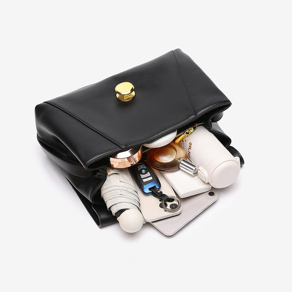 Structured flap shoulder bag with round gold-tone clasp and long flat strap in smooth matte leather-look finish, detail view