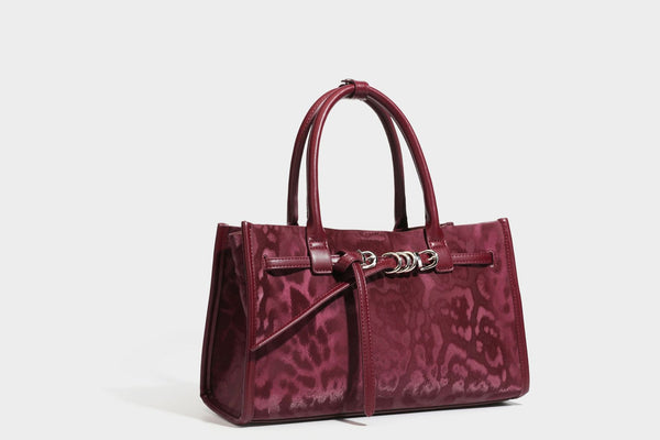Structured leopard-print tote bag with glossy satin-like finish, dual rounded top handles, silver buckle-and-ring front