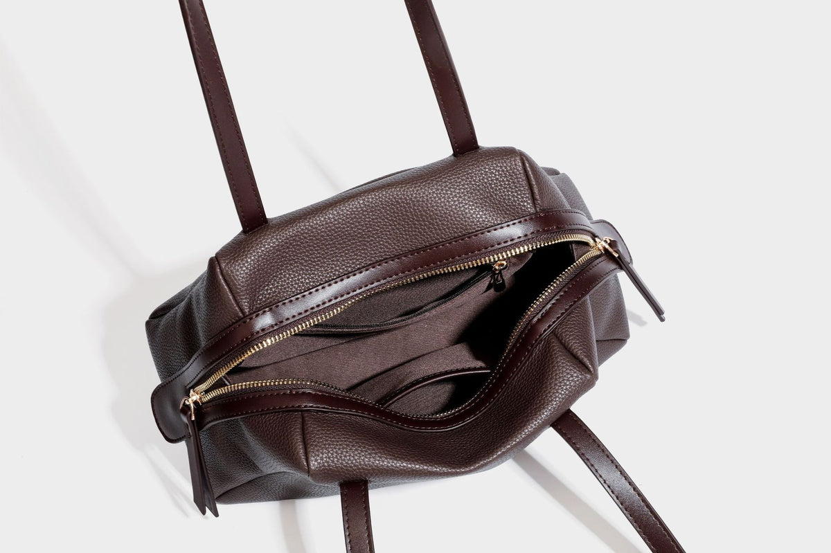 Structured trapezoid shoulder bag in dark brown pebbled leather-look finish with slim double straps, top zip closure, side