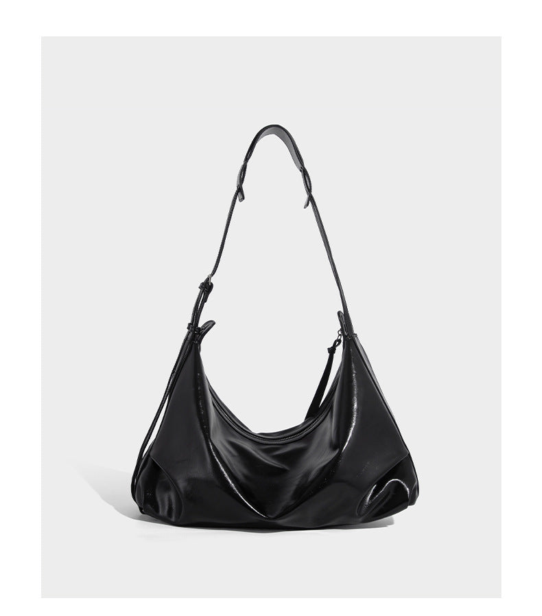 Glossy black slouchy hobo shoulder bag with zip closure, silver-tone ring hardware, and adjustable crossbody strap, detail