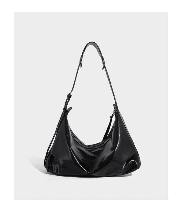 Glossy black slouchy hobo shoulder bag with zip closure, silver-tone ring hardware, and adjustable crossbody strap, detail
