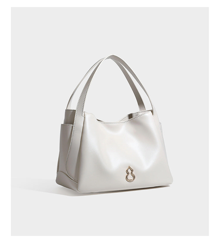 Structured glossy leather-look tote shoulder bag with dual top handles, detachable crossbody strap, side pockets, and, detail