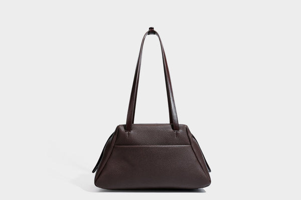 Structured trapezoid shoulder bag in dark brown pebbled leather-look finish with slim double straps, top zip closure, side