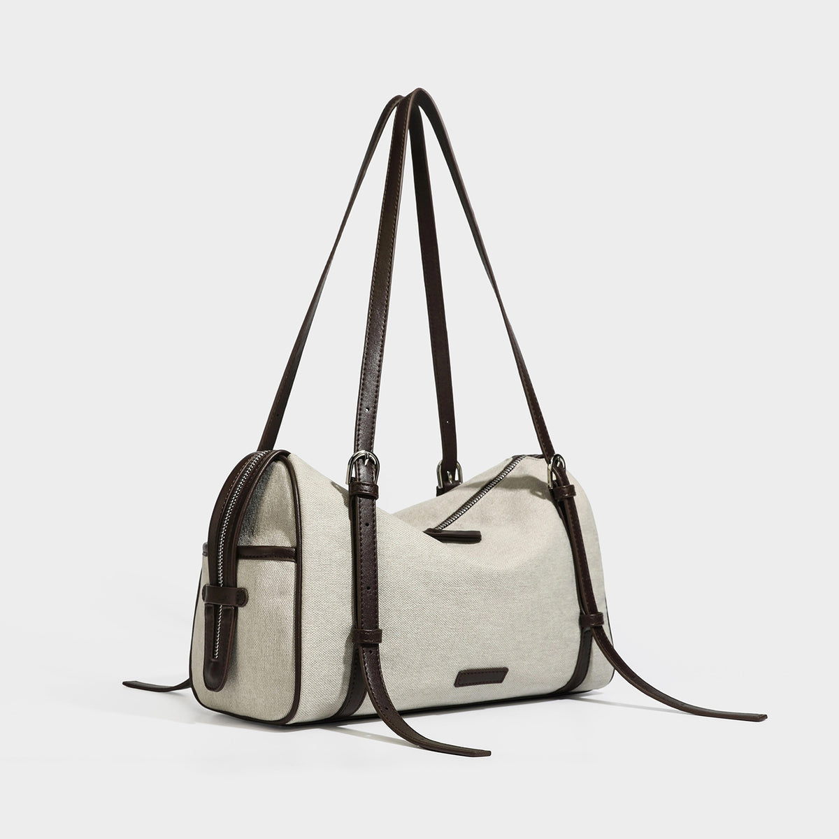 Beige canvas barrel bag with dark brown leather-look trim, silver-tone hardware, top zip closure, and adjustable shoulder