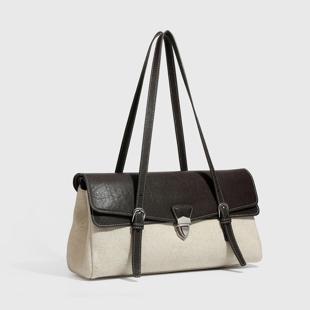 Structured two-tone shoulder bag with black leather-look flap, cream woven-texture body, silver turn-lock clasp, and double