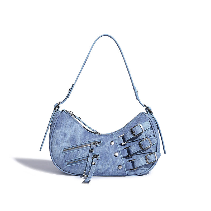 Crescent shoulder bag in washed blue denim-look PU with stacked buckle straps, front zip pocket, and silver-tone hardware