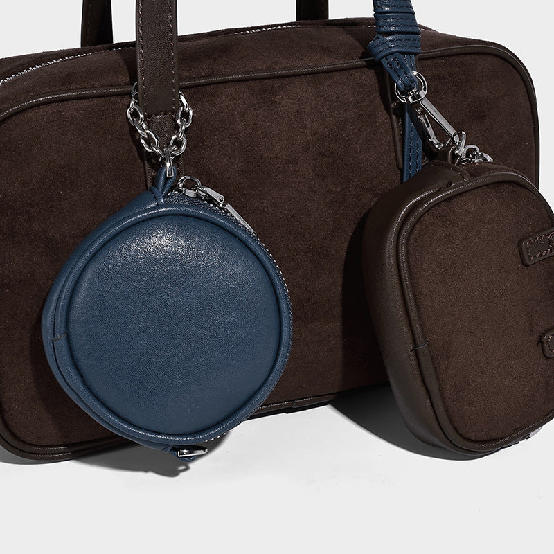 Strukturierte Boston-Bowlingtasche in Veloursleder-Optik, dunkelbraun, mit Henkeln mit blauen Akzenten und abnehmbarem Mini-Rundtäschchen, Detailaufnahme