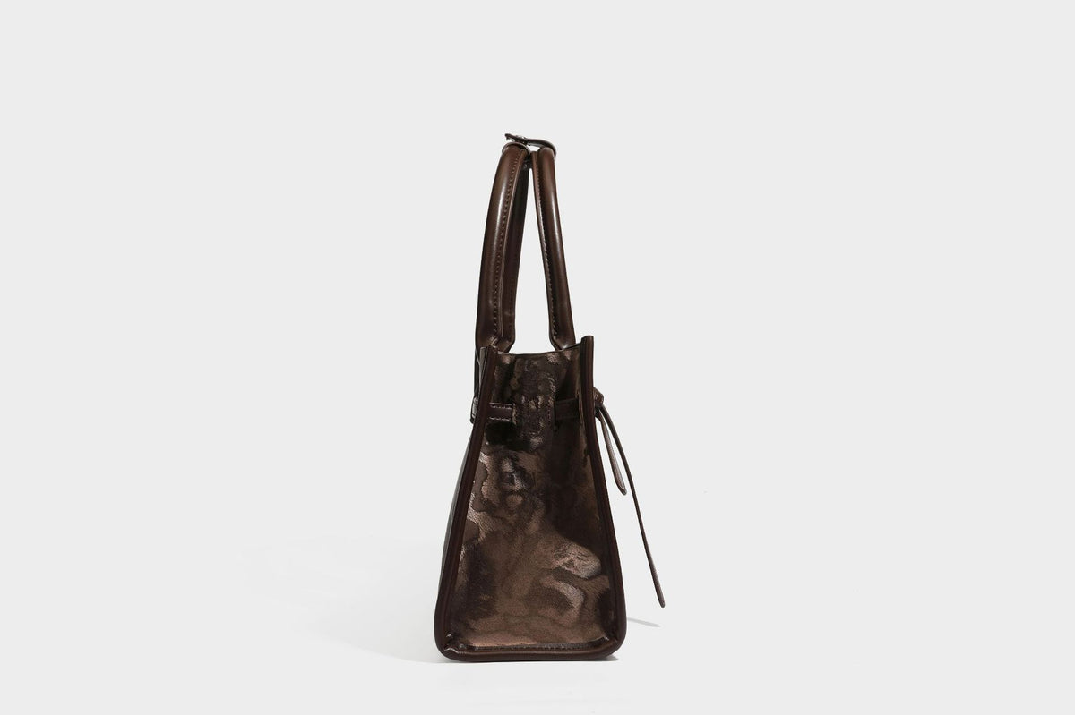 Structured leopard-print tote bag with glossy satin-like finish, dual rounded top handles, silver buckle-and-ring front