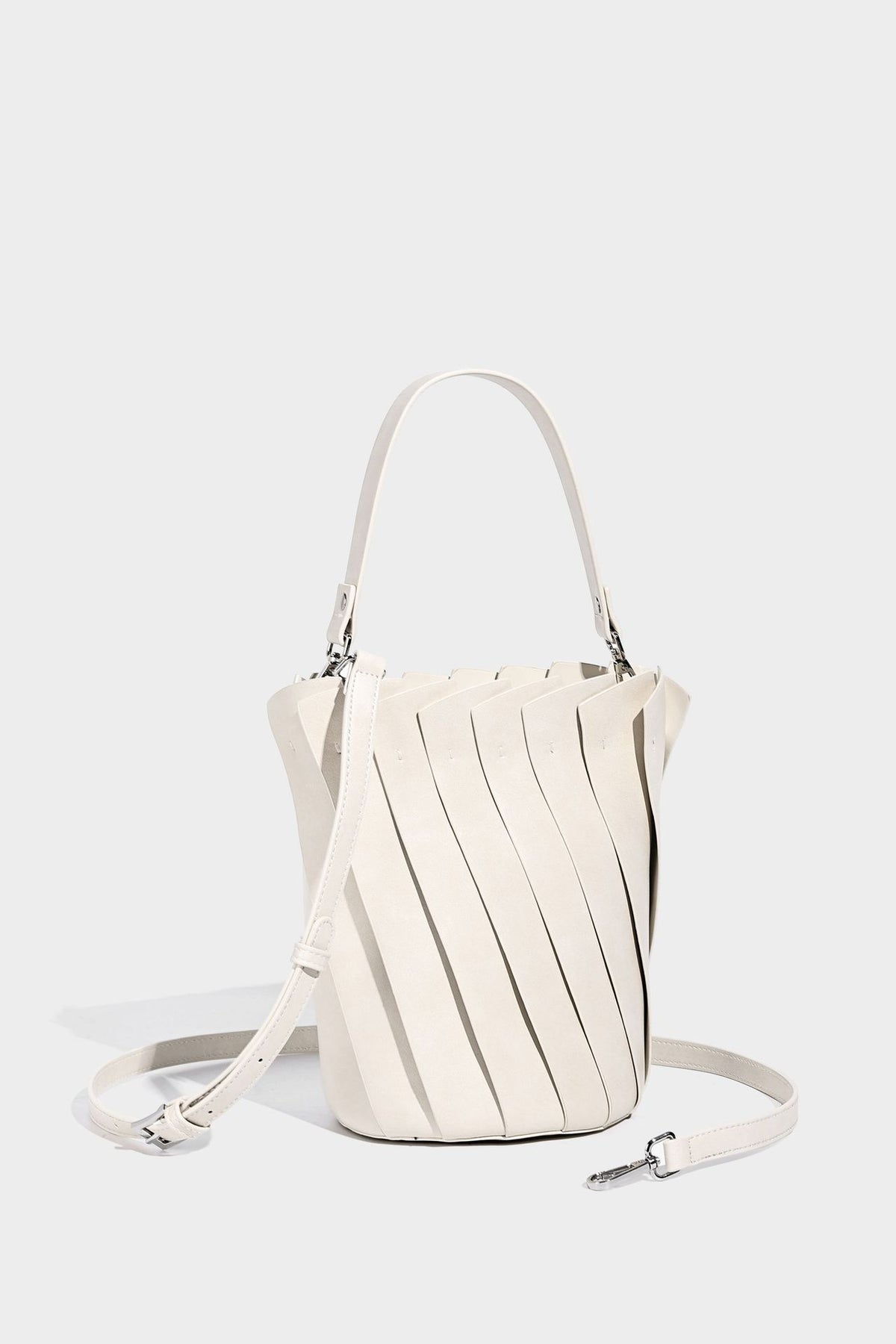 Structured pleated-panel bucket bag with curved top handle and detachable adjustable shoulder strap in smooth matte, detail