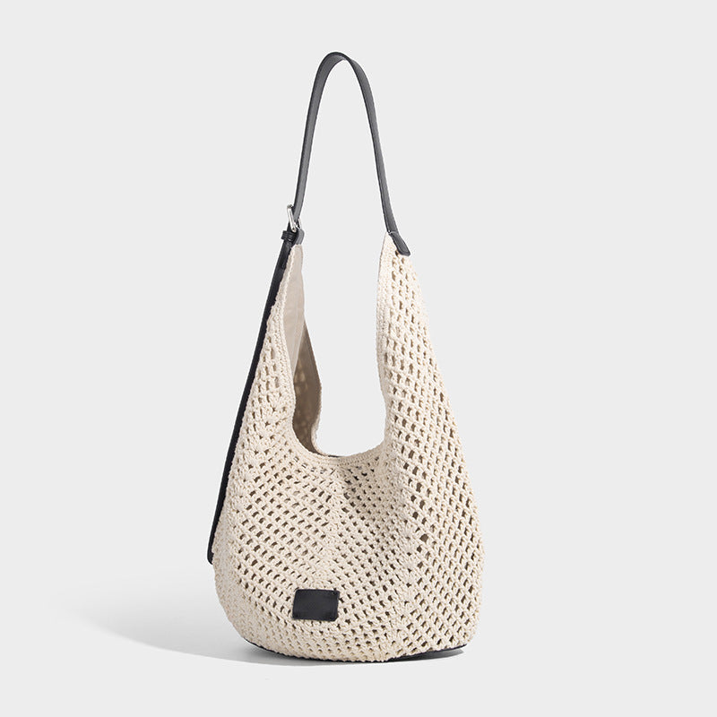 Cream openwork crochet hobo bag with black leather-look strap and trim patch accent, slouchy teardrop silhouette, detail view