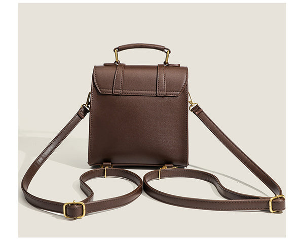 Structured mini satchel backpack with smooth leather-look finish, front flap pocket, gold-tone stud closures, and top handle