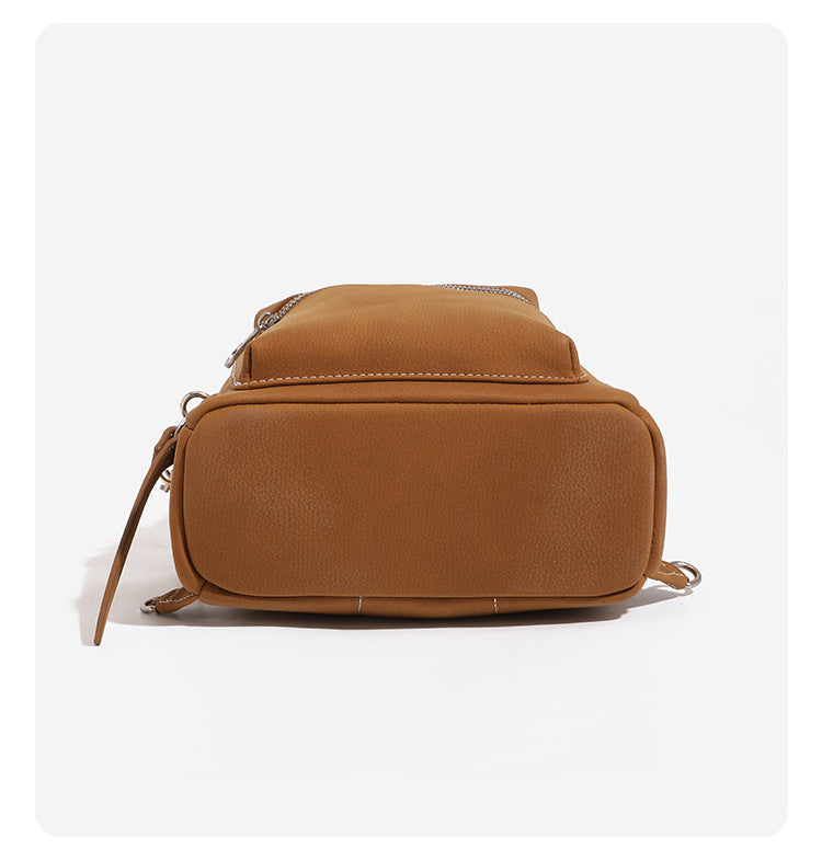 Small rounded mini backpack handbag in pebbled leather-look finish with front zip pocket, silver-tone hardware, and, detail