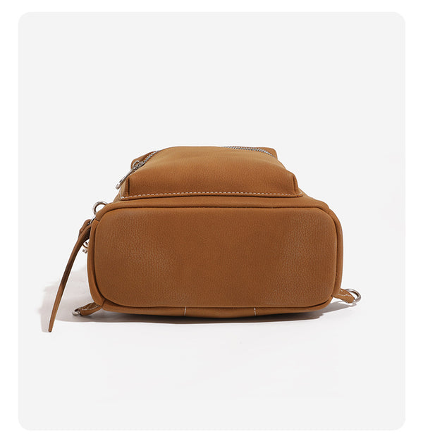 Small rounded mini backpack handbag in pebbled leather-look finish with front zip pocket, silver-tone hardware, and, detail