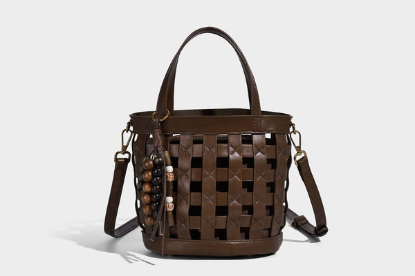Small woven lattice bucket bag in brown leather-look finish with beaded tassel charm, dual top handles, and detachable