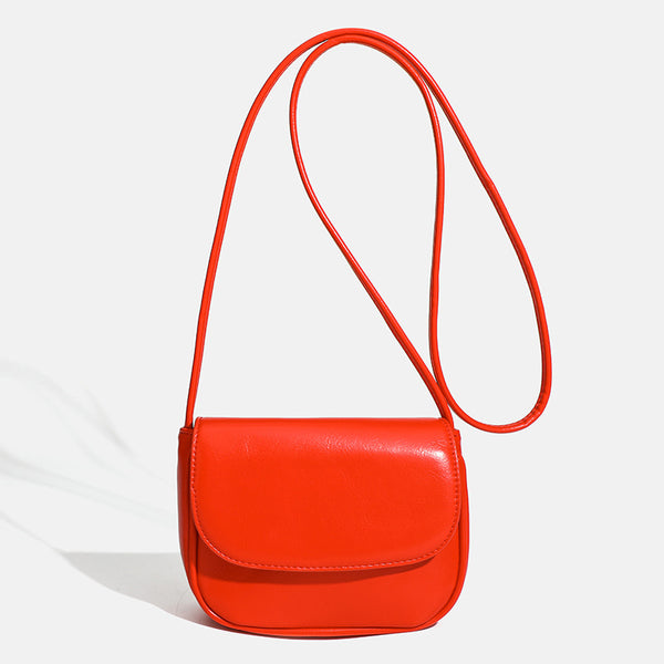 Compact rounded rectangular flap crossbody bag with glossy leather-look finish and long shoulder strap, front view