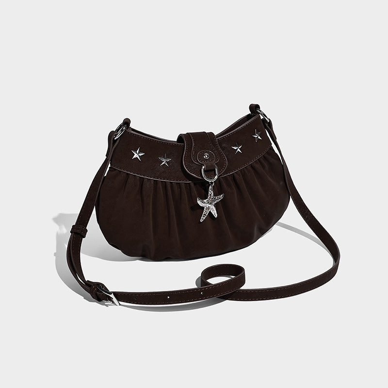 Ruched shoulder bag with curved flap, silver star studs, dangling starfish charm, and adjustable crossbody strap, front view