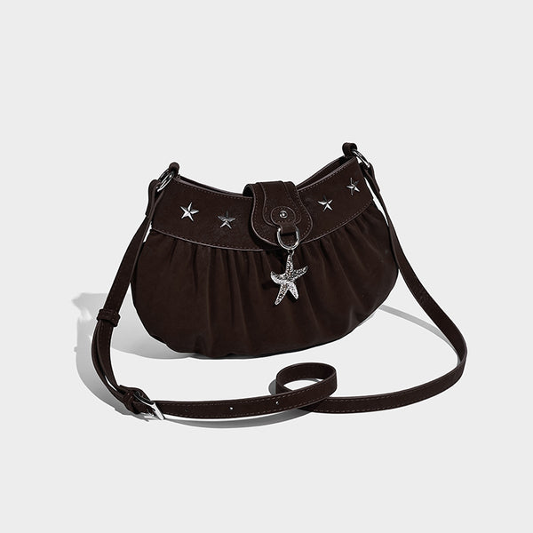 Ruched shoulder bag with curved flap, silver star studs, dangling starfish charm, and adjustable crossbody strap, front view
