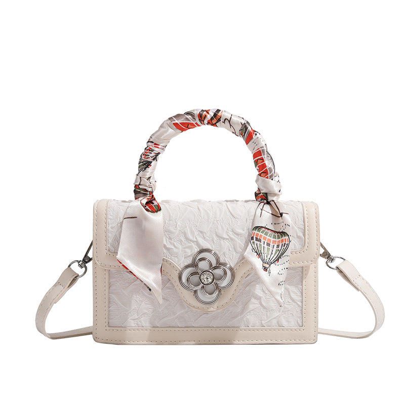 Ivory structured mini crossbody bag with crinkled leather-look finish, silk scarf top handle, silver four-petal flower clasp