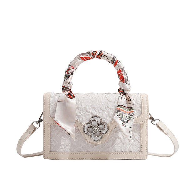 Ivory structured mini crossbody bag with crinkled leather-look finish, silk scarf top handle, silver four-petal flower clasp