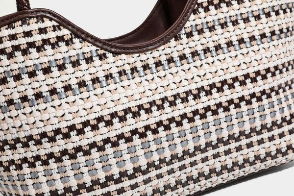 Large woven checker-pattern tote bag with dark braided shoulder straps, leather-look trim, and drawstring side ties, detail
