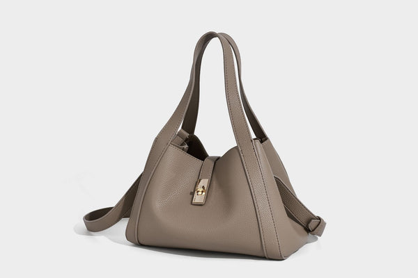 Structured trapezoid tote bag in taupe pebbled leather-look finish with gold-tone turn-lock hardware, dual top handles, and