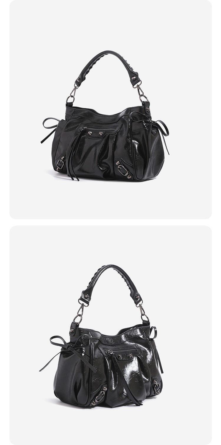 Slouchy glossy crinkle leather-look shoulder bag with silver stud accents, tassel ties, front zip pocket, and top handle