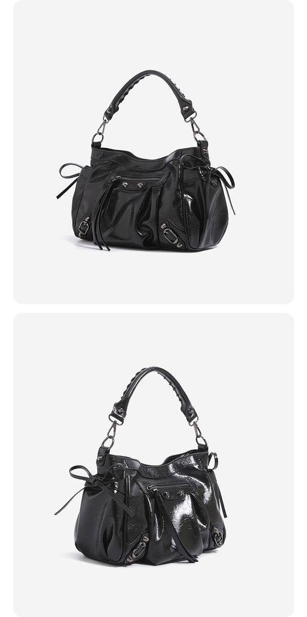 Slouchy glossy crinkle leather-look shoulder bag with silver stud accents, tassel ties, front zip pocket, and top handle