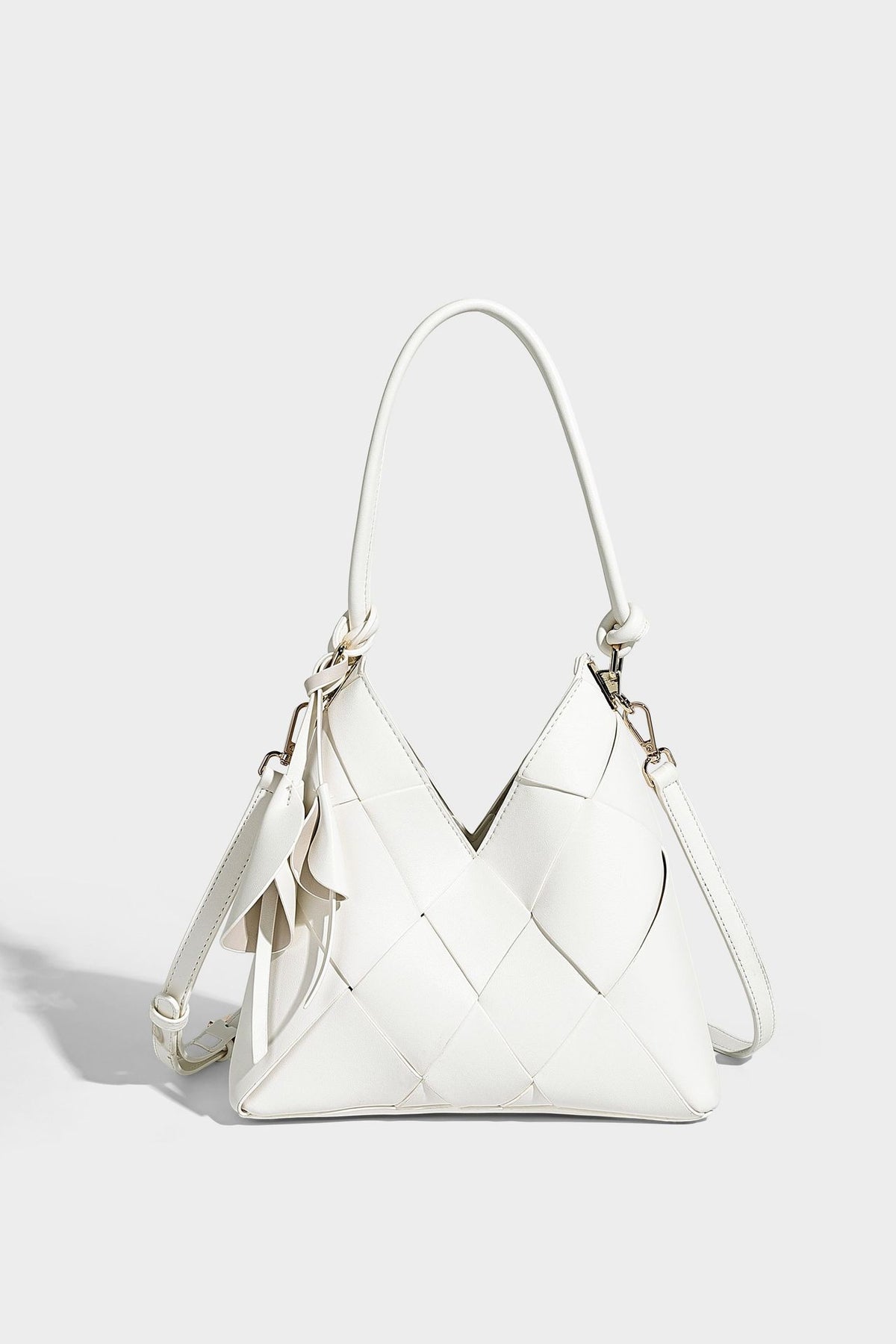 Compact bucket shoulder bag with black-and-white diamond patchwork panels, knotted top handle, gold-tone hardware, and
