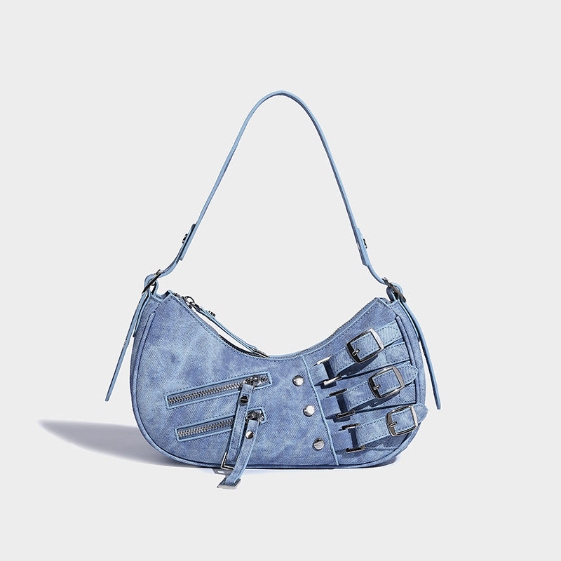 Crescent shoulder bag in washed blue denim-look PU with stacked buckle straps, front zip pocket, and silver-tone hardware