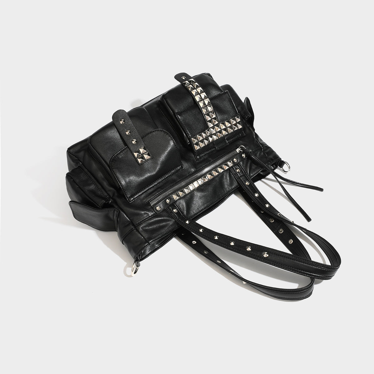 Black leather-look tote bag with silver pyramid studs on handles and front panel, multiple flap and zip exterior pockets